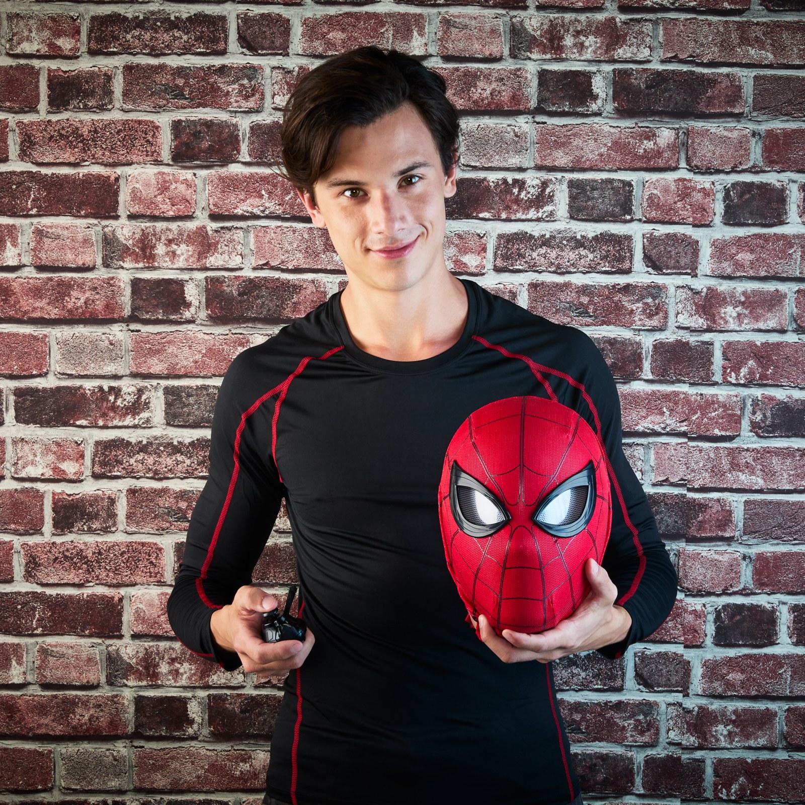 Person holding the Spider-Man mask and wired remote control