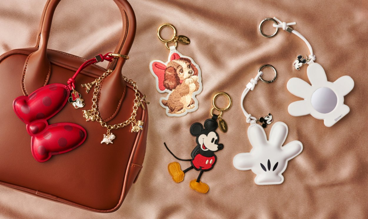 Disney Store Japan Fashion Charm accessories displayed beside a brown handbag