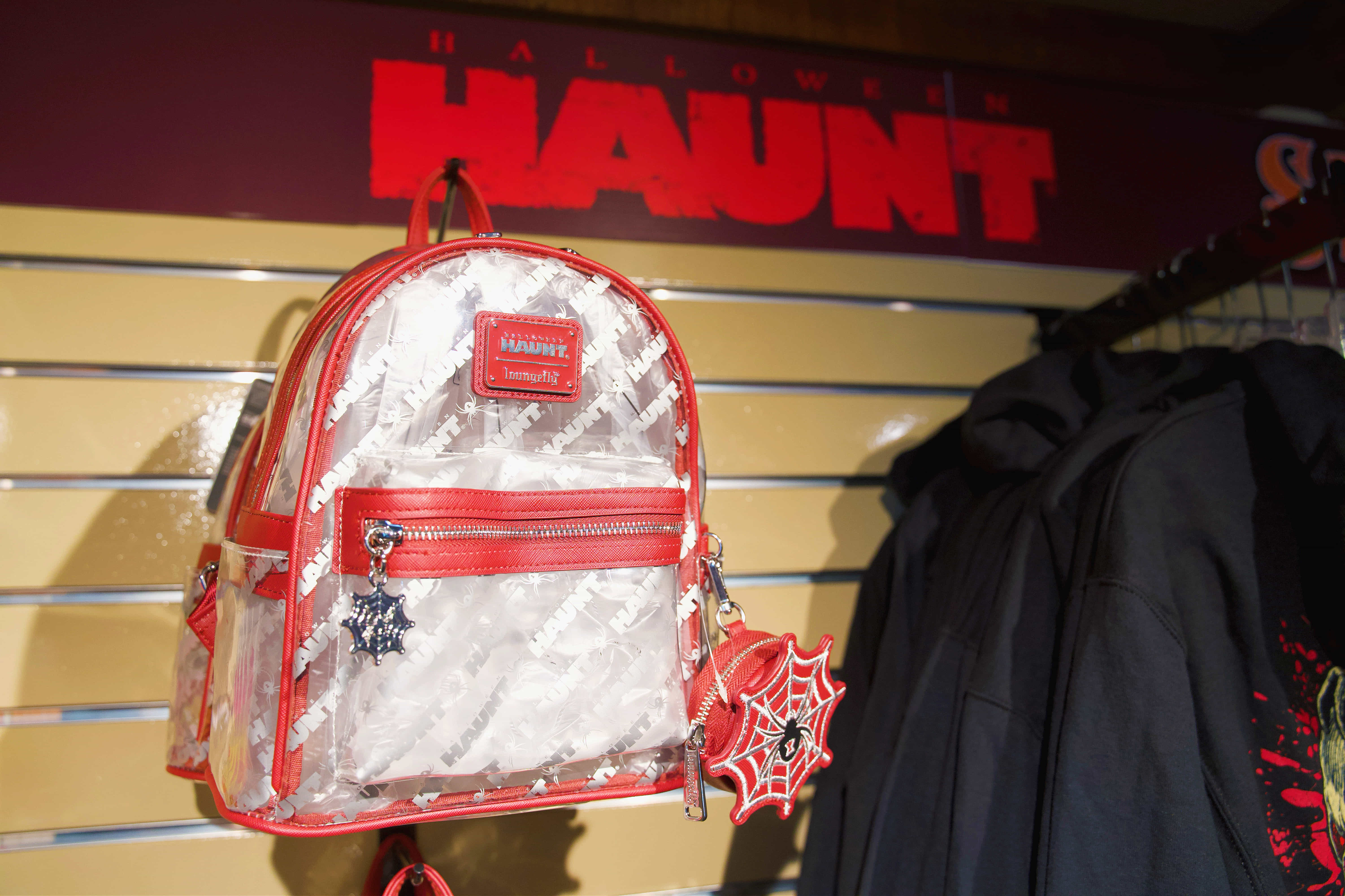Clear Dorney Park HAUNT backpack with red trim, web charm and lantern detail