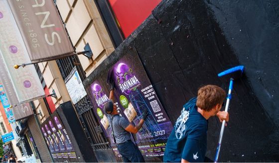 Workers place Bakunawa posters on a Philadelphia street
