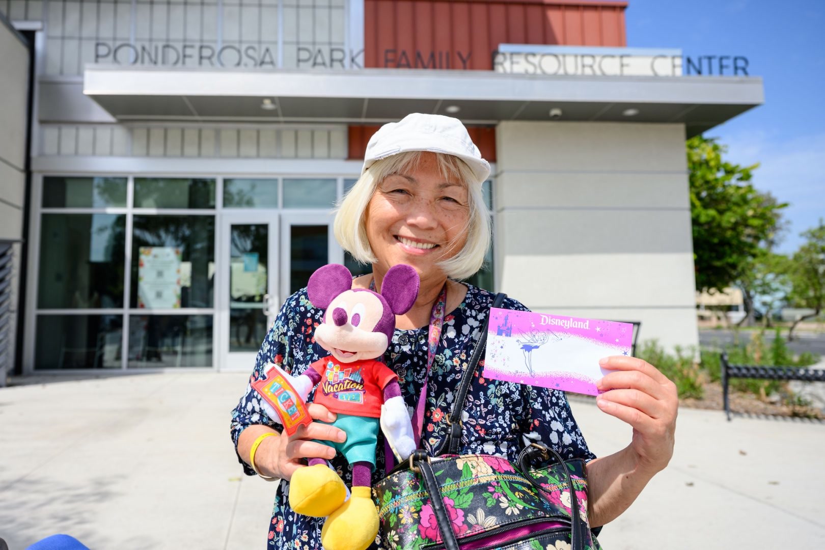 An Anaheim senior holds a Mickey Mouse plush and Disneyland Resort ticket at Ponderosa Family Resource Center
