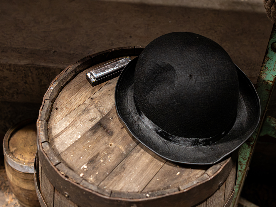 A black hat and harmonica on a barrel inside Universal Orlando's Sinners haunted house