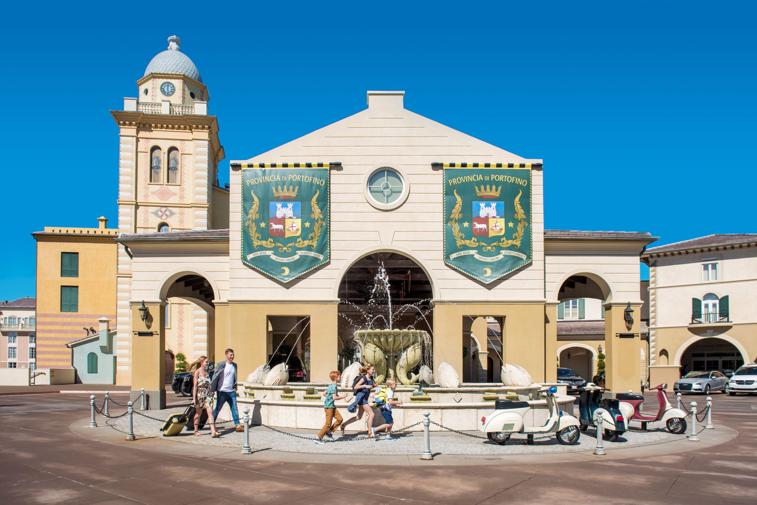 Portofino Bay Hotel entrance with a clock tower, fountain and Italian-style banners