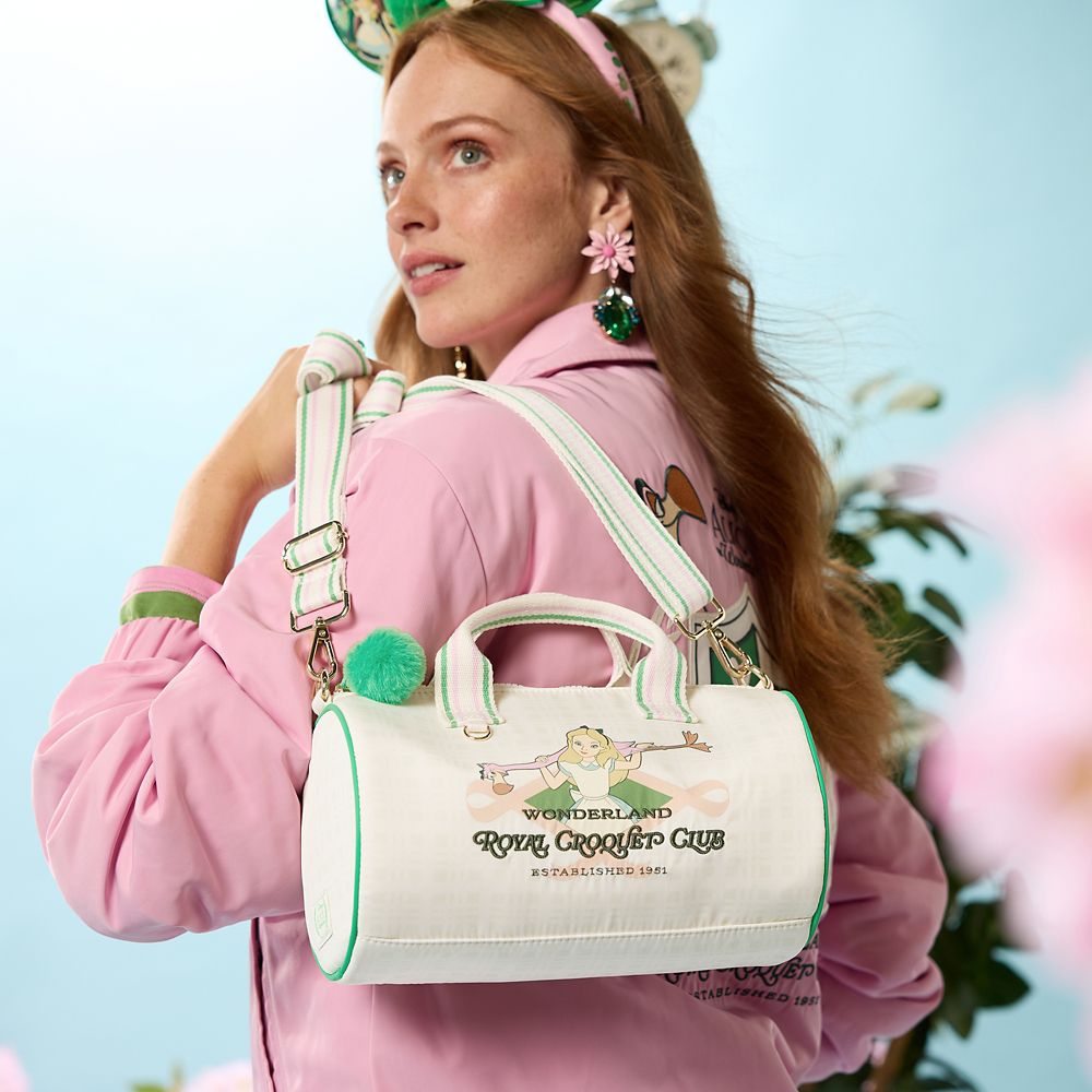 Alice in Wonderland crossbody bag worn over the shoulder, showing the striped strap and green pom-pom