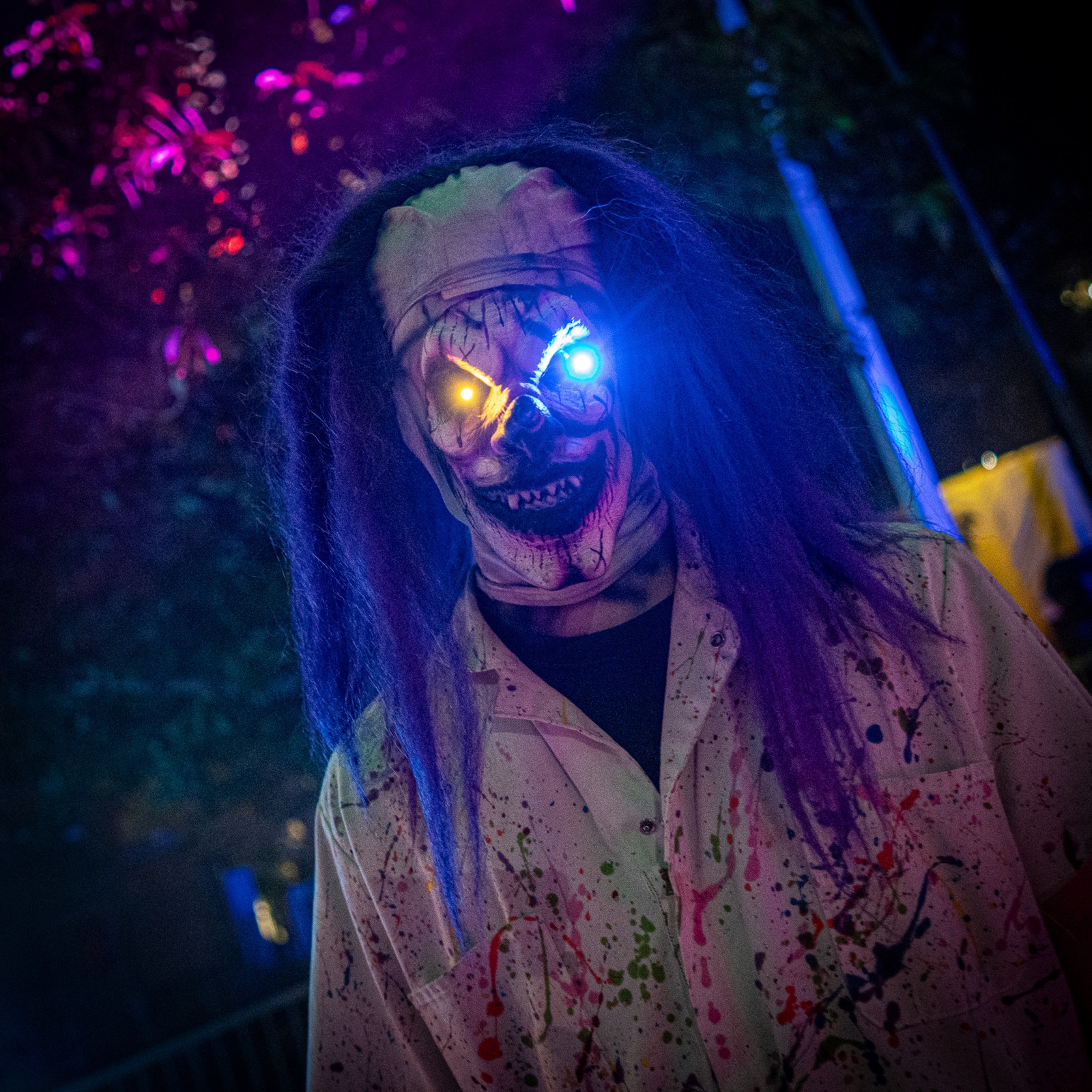 A Dorney Park Halloween Haunt character in a purple and blue-lit wooded setting