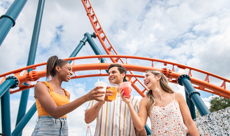 SeaWorld Orlando guests holding drinks beneath a roller coaster