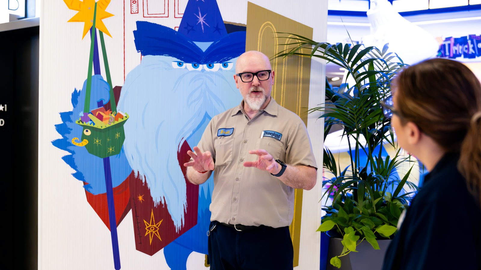 Disneyland Resort artist Brett standing beside Monsters, Inc. Halloween artwork at Pixar Place Hotel