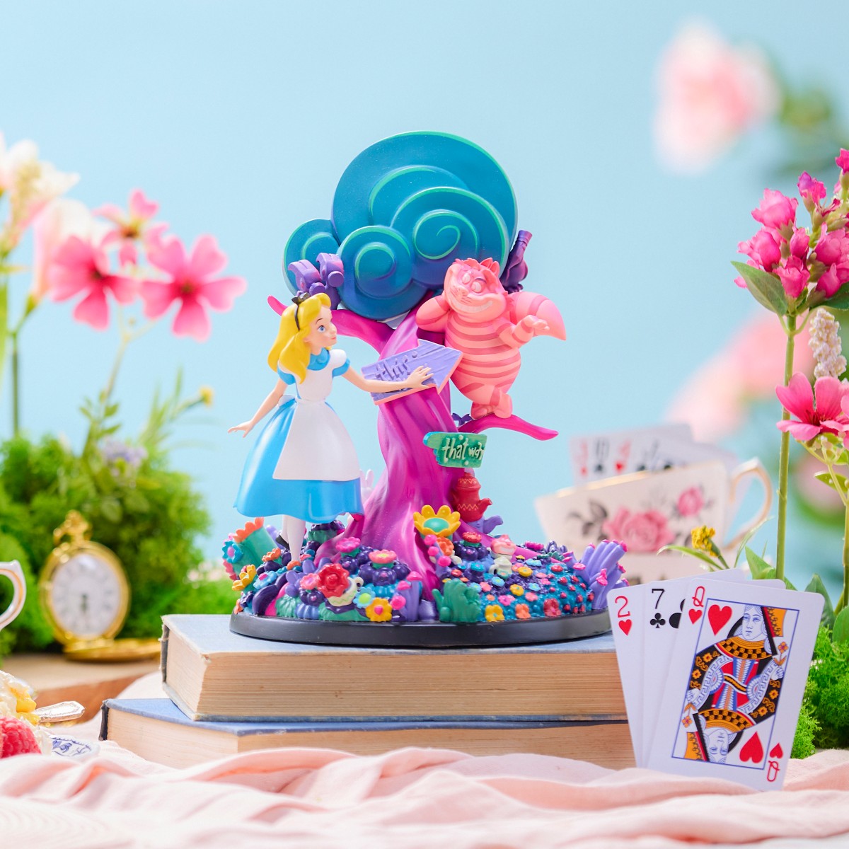 Alice in Wonderland figure displayed with flowers, books and playing cards
