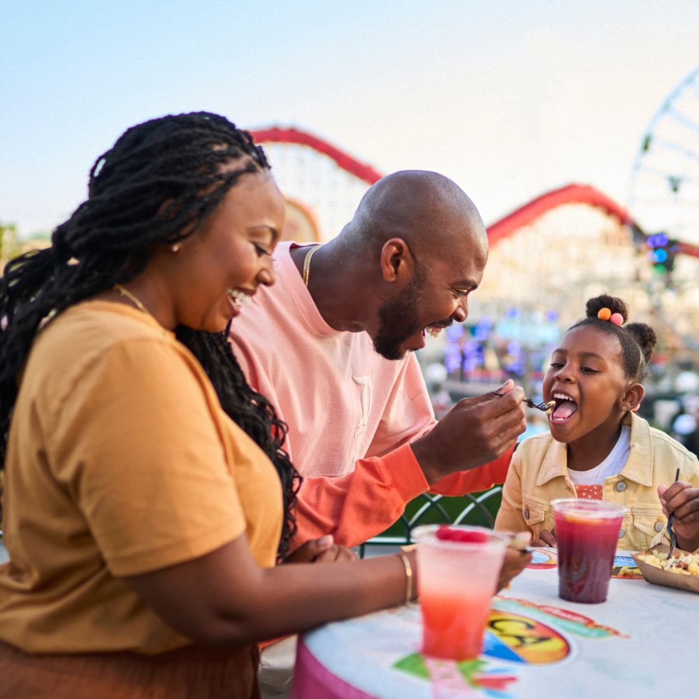 Family dining at Paradise Gardens Park with Pixar Pier attractions in the background