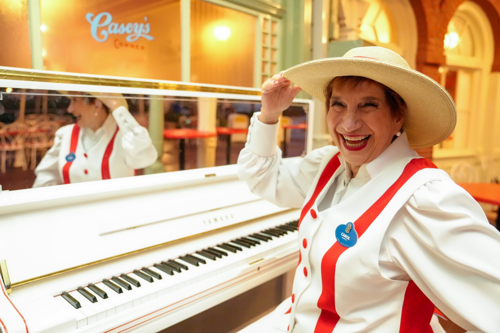 Carol smiles beside the piano at Casey’s Corner in Magic Kingdom