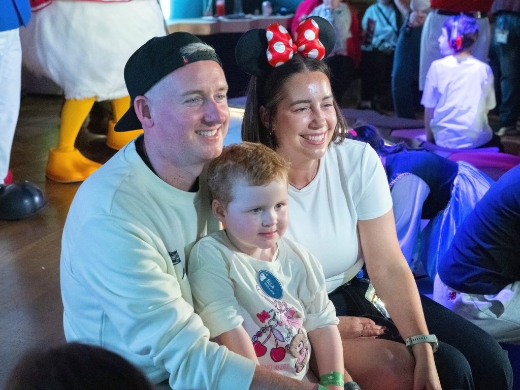 A child seated with two adults at the Disney wish-family gathering