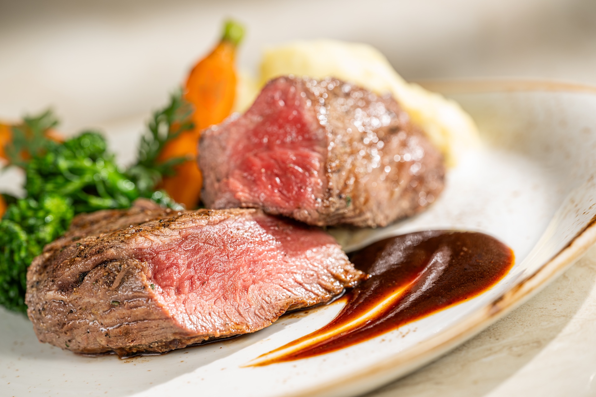 Char-grilled steak sliced beside vegetables and sauce