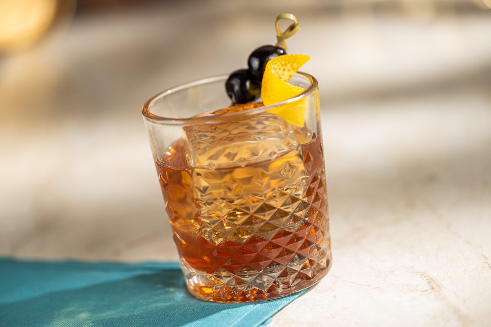 An Old Fashioned cocktail garnished with cherries and orange peel