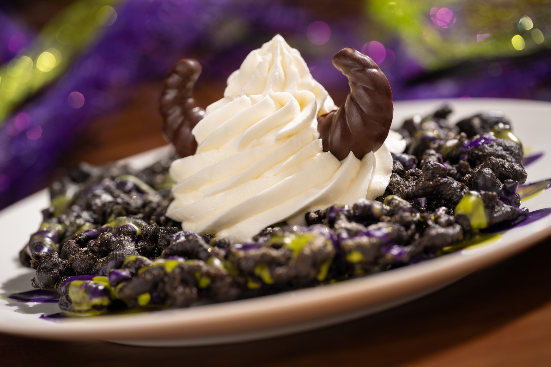 Maleficent Funnel Cake topped with vanilla soft-serve, purple and green icing, and chocolate horns