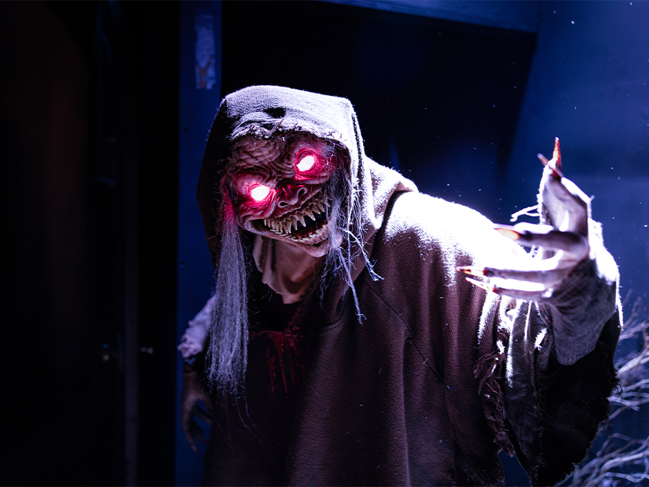 A glowing-eyed monster reaching toward guests inside the Killceañera house