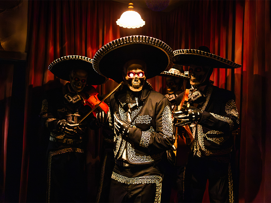 Skeleton musicians in black mariachi suits inside the Killceañera house
