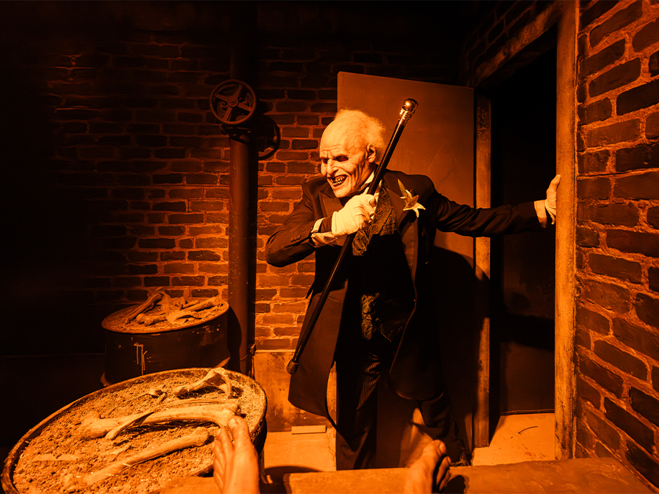 A pale funeral-home character holds a cane inside Dead, Deader, Deadest