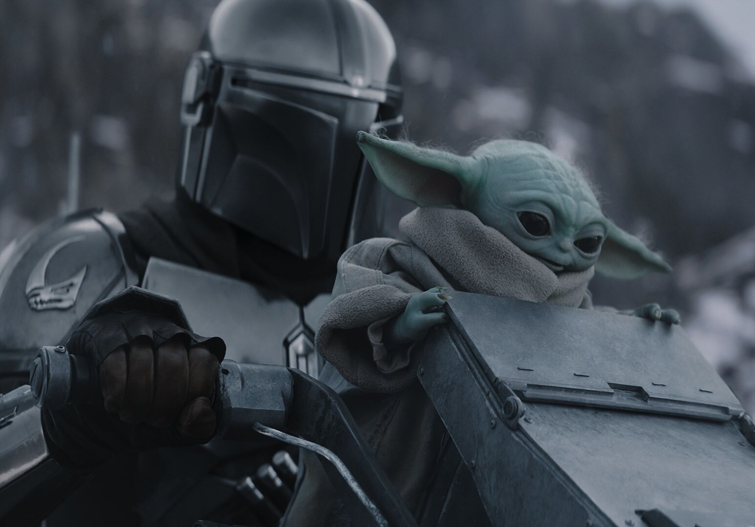 The Mandalorian holds Grogu in an official Lucasfilm still from Star Wars: The Mandalorian and Grogu