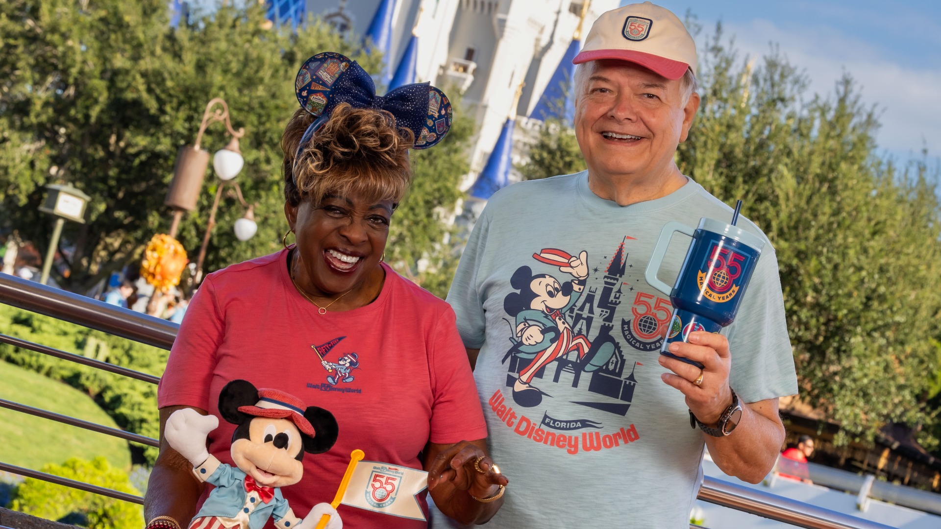 Walt Disney World opening-day cast members Earliene and Frank wearing 55th-anniversary merchandise near Cinderella Castle