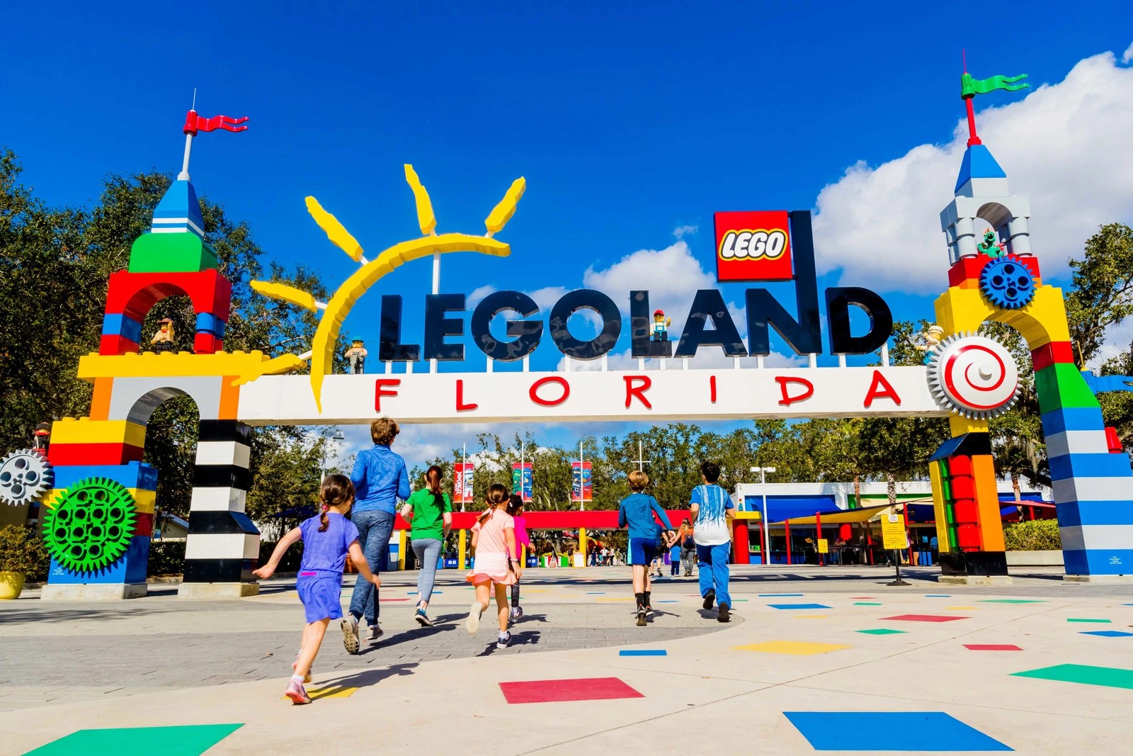 Families walk beneath the colorful LEGOLAND Florida entrance sign