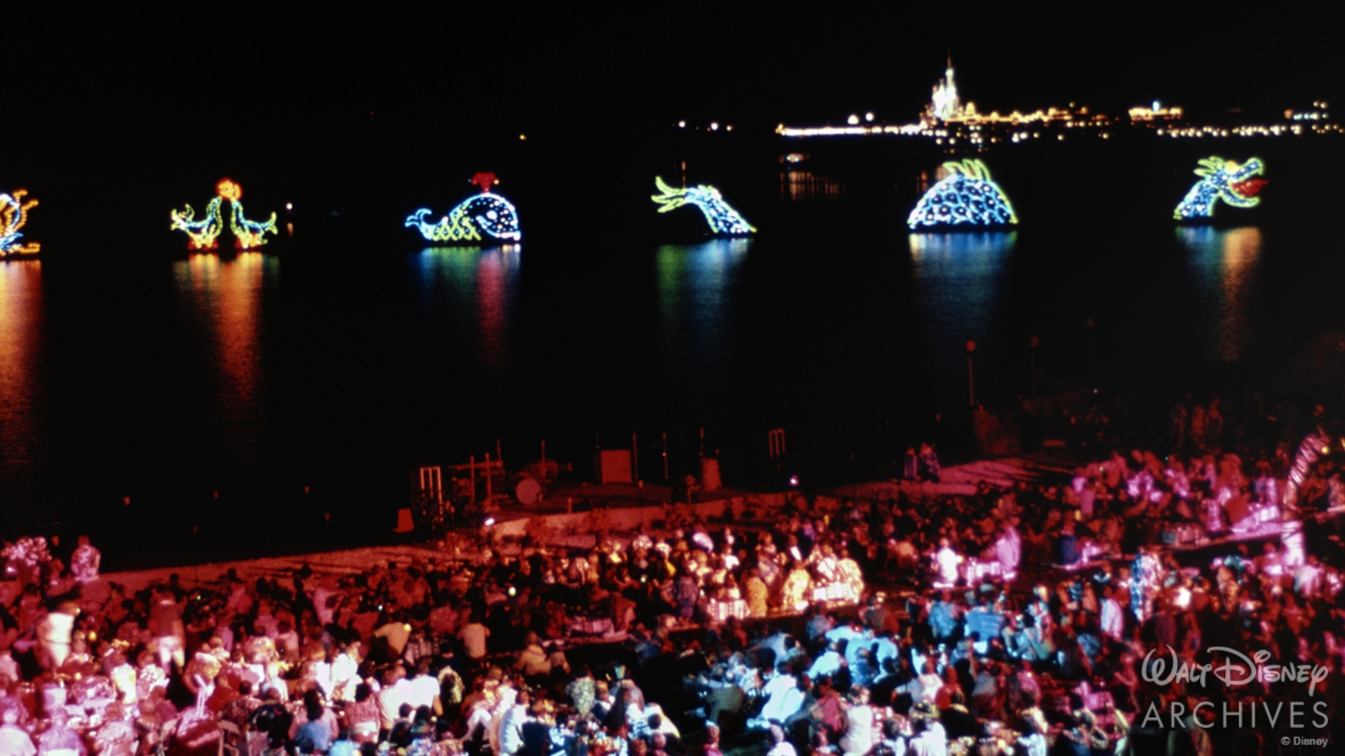 Guests watch the Electrical Water Pageant from the Polynesian beach on October 24, 1971