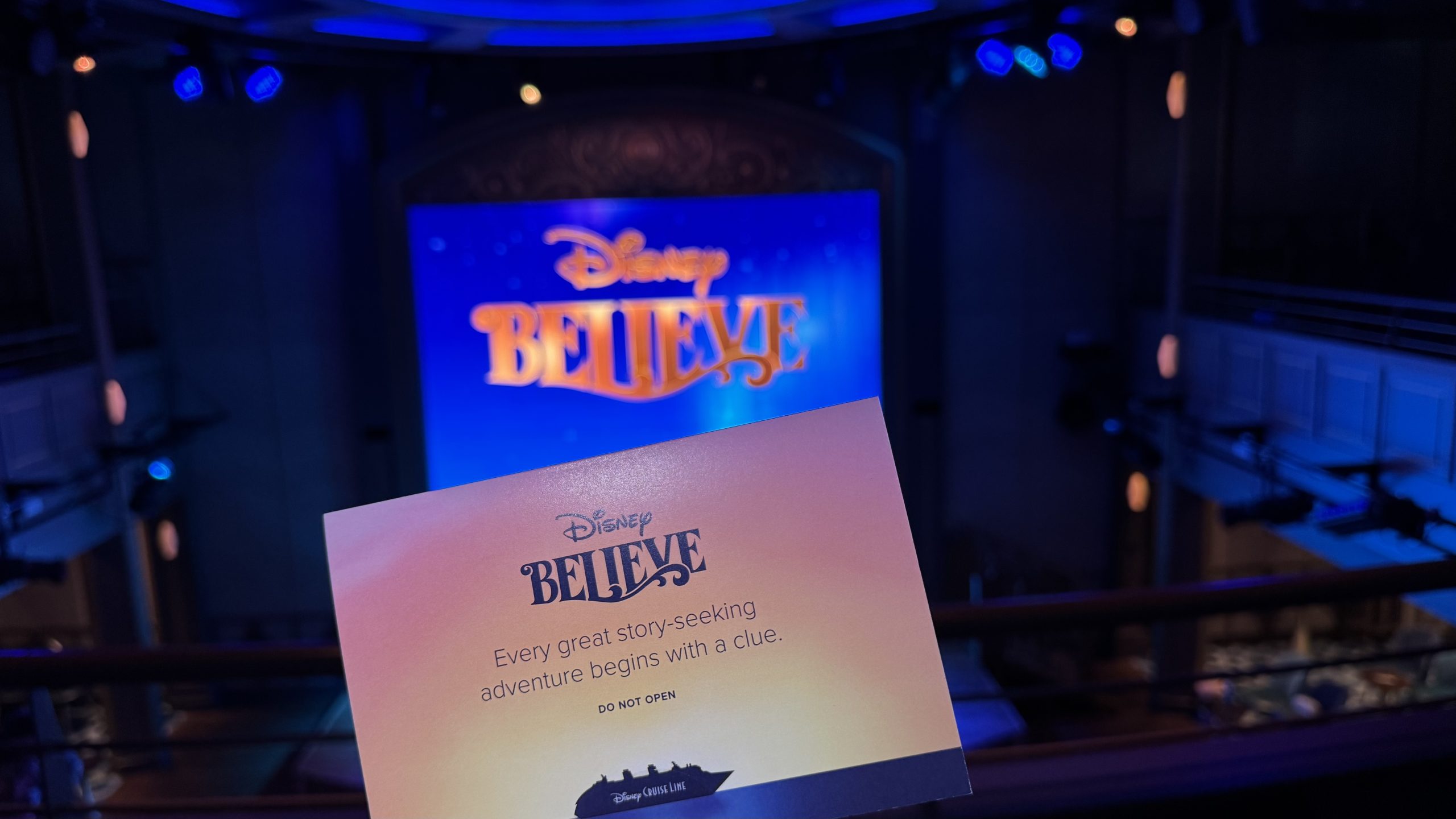 A Disney Believe scavenger-hunt envelope displayed in front of the ship’s logo during a preview aboard Disney Wish