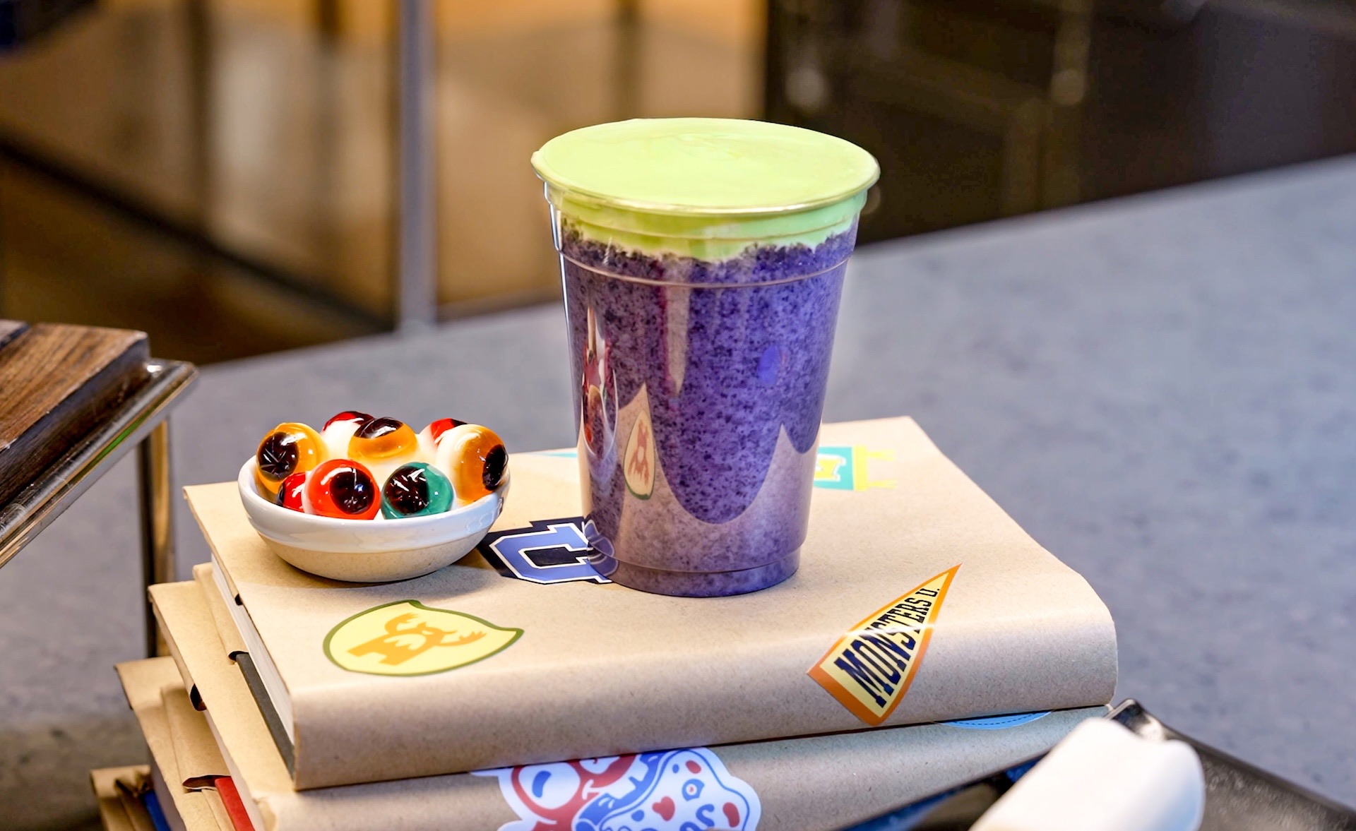A purple frozen Blort drink with green foam beside monster-themed snacks