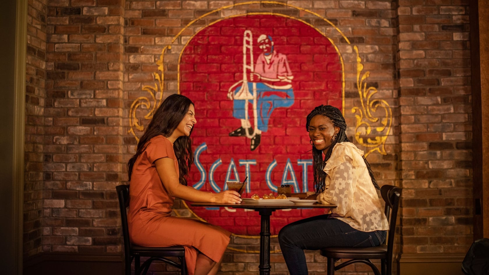 Two guests seated at a table inside Scat Cat’s Club – Lounge at Disney’s Port Orleans Resort – French Quarter