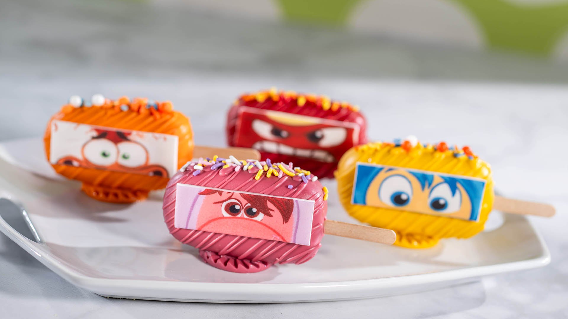 Four colorful Inside Out cake popsicles themed to Anxiety, Joy, Embarrassment and Anger