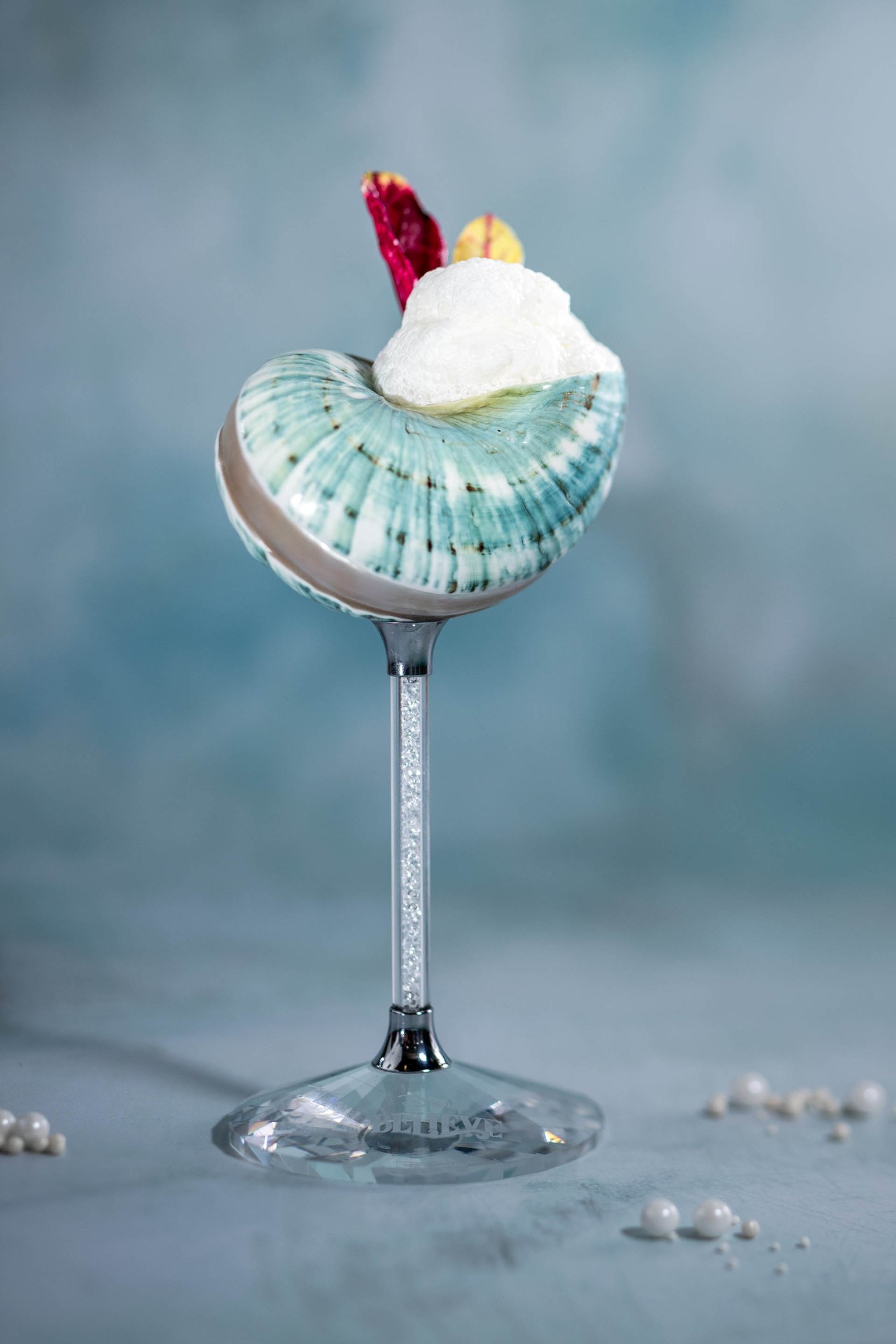 Blue Sea Salt Martini topped with foam in a shell-shaped glass