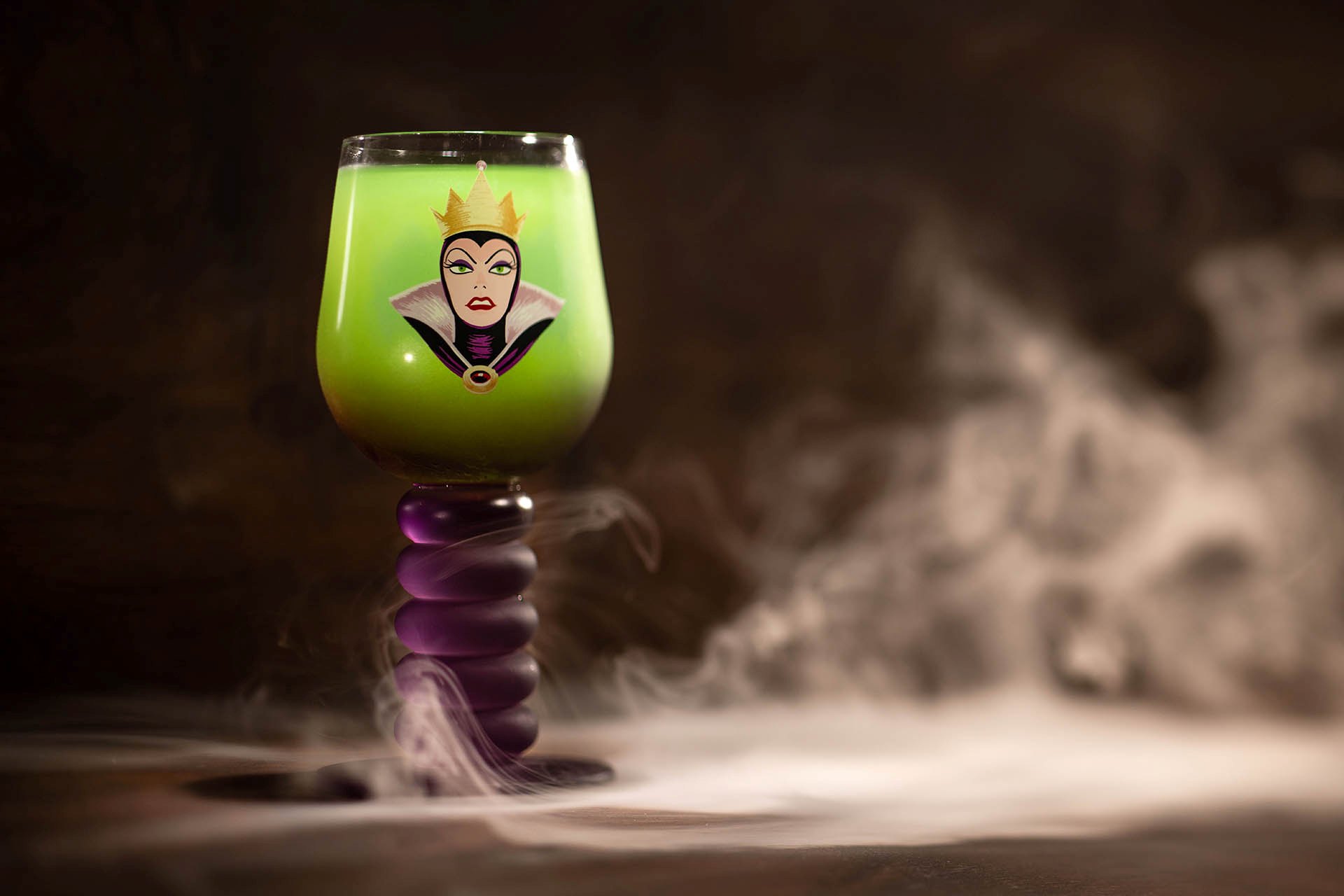 Green Peddler's Disguise drink in an Evil Queen glass surrounded by theatrical fog