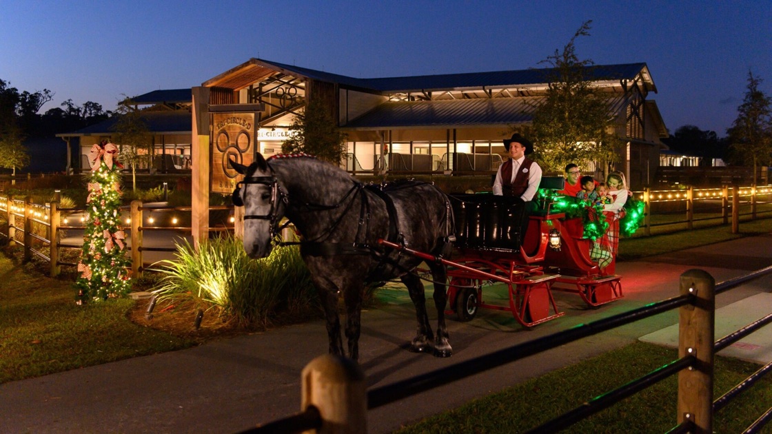A family rides in a horse-drawn holiday sleigh at Disney’s Fort Wilderness Resort