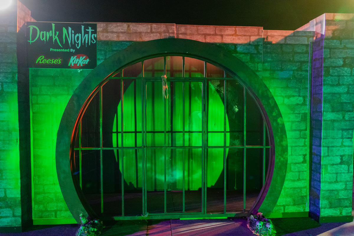 The Descent drainage pipe set piece lit green at Hersheypark Dark Nights