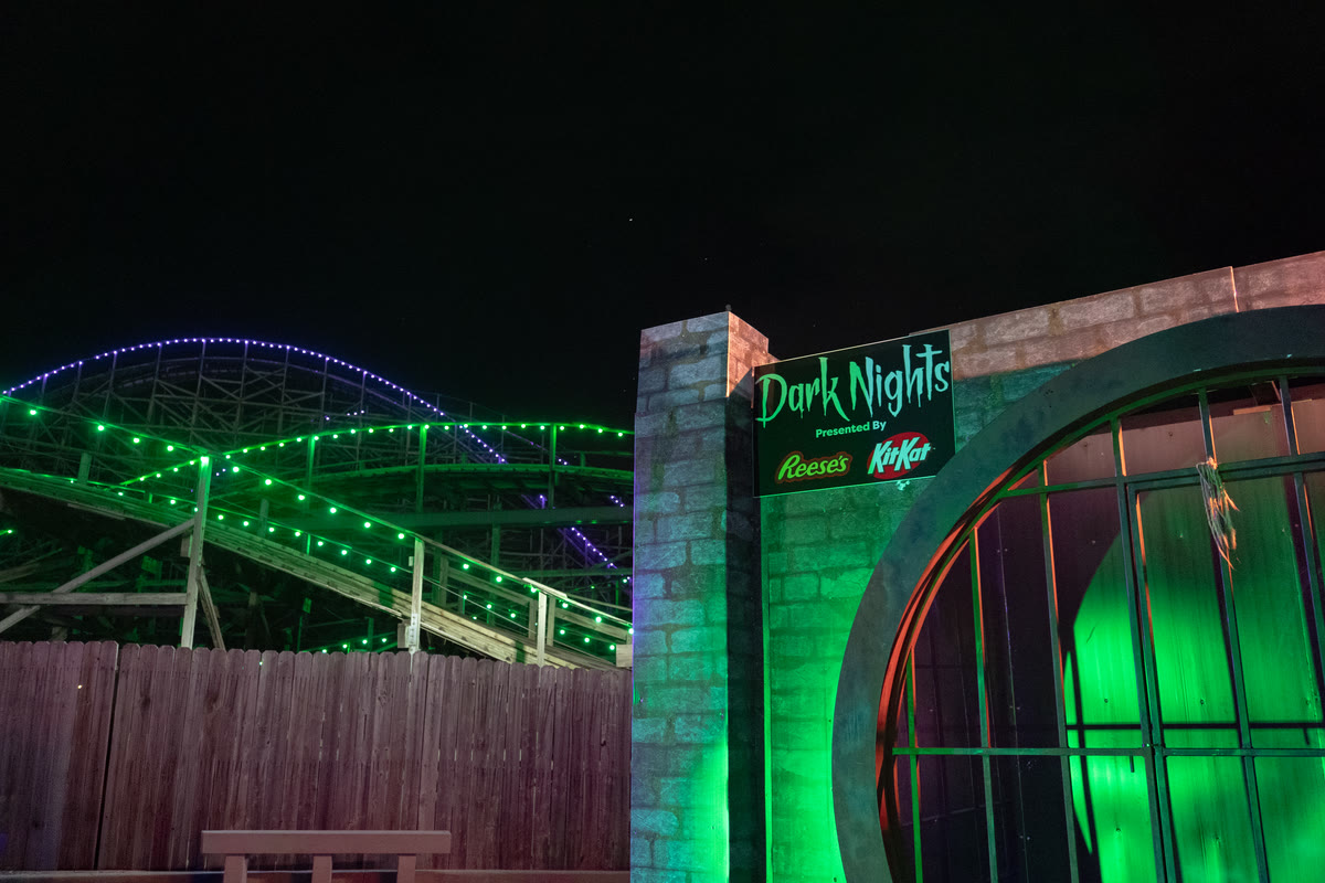The Descent drainage pipe photo spot with Lightning Racer behind it at Hersheypark Dark Nights