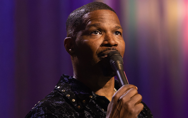 Jamie Foxx holds a microphone onstage in an official Hulu publicity still