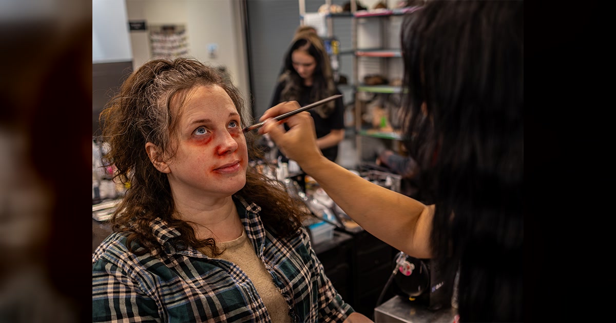 A Universal Horror Unleashed artist applies character makeup to a performer