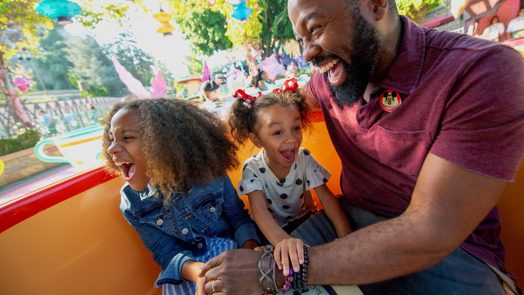 A father and two daughters ride Mad Tea Party at Disneyland