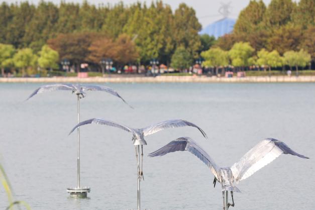 Close view of three Siberian crane sculptures over Wishing Star Lake