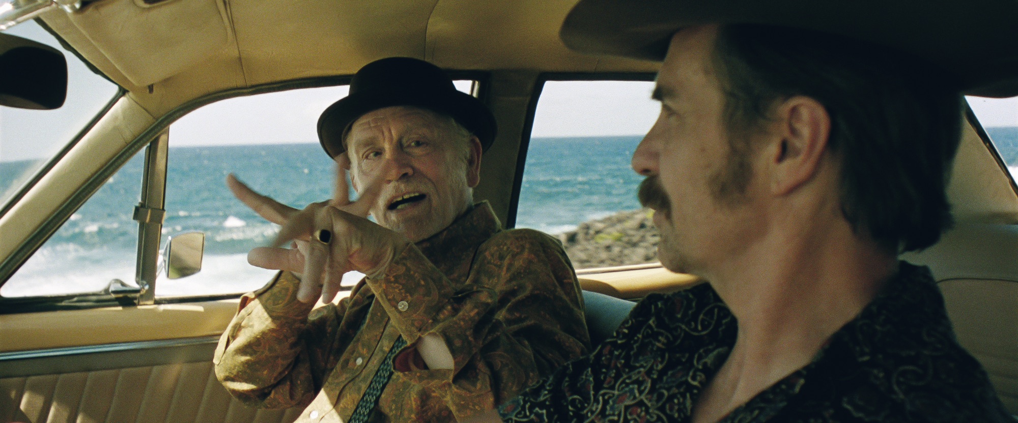 John Malkovich gestures while Sam Rockwell sits beside him in Wild Horse Nine