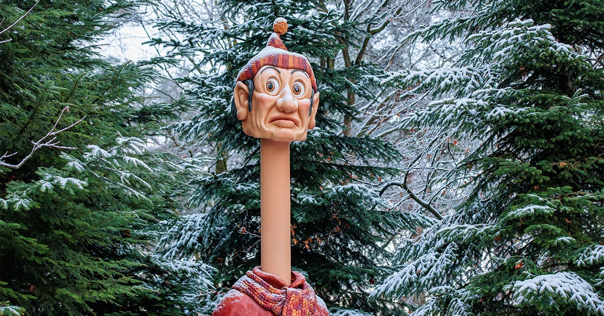 Long Neck wearing a winter hat and scarf among snow-covered trees at Efteling