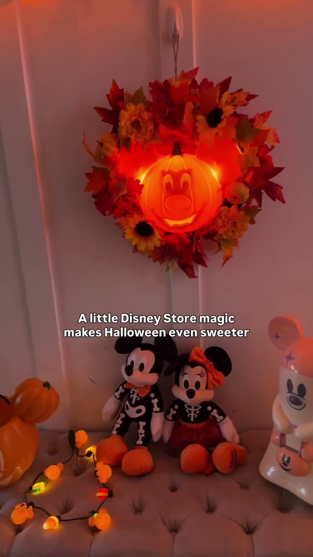 Glowing Mickey pumpkin wreath above Mickey and Minnie plush in skeleton-themed Halloween outfits