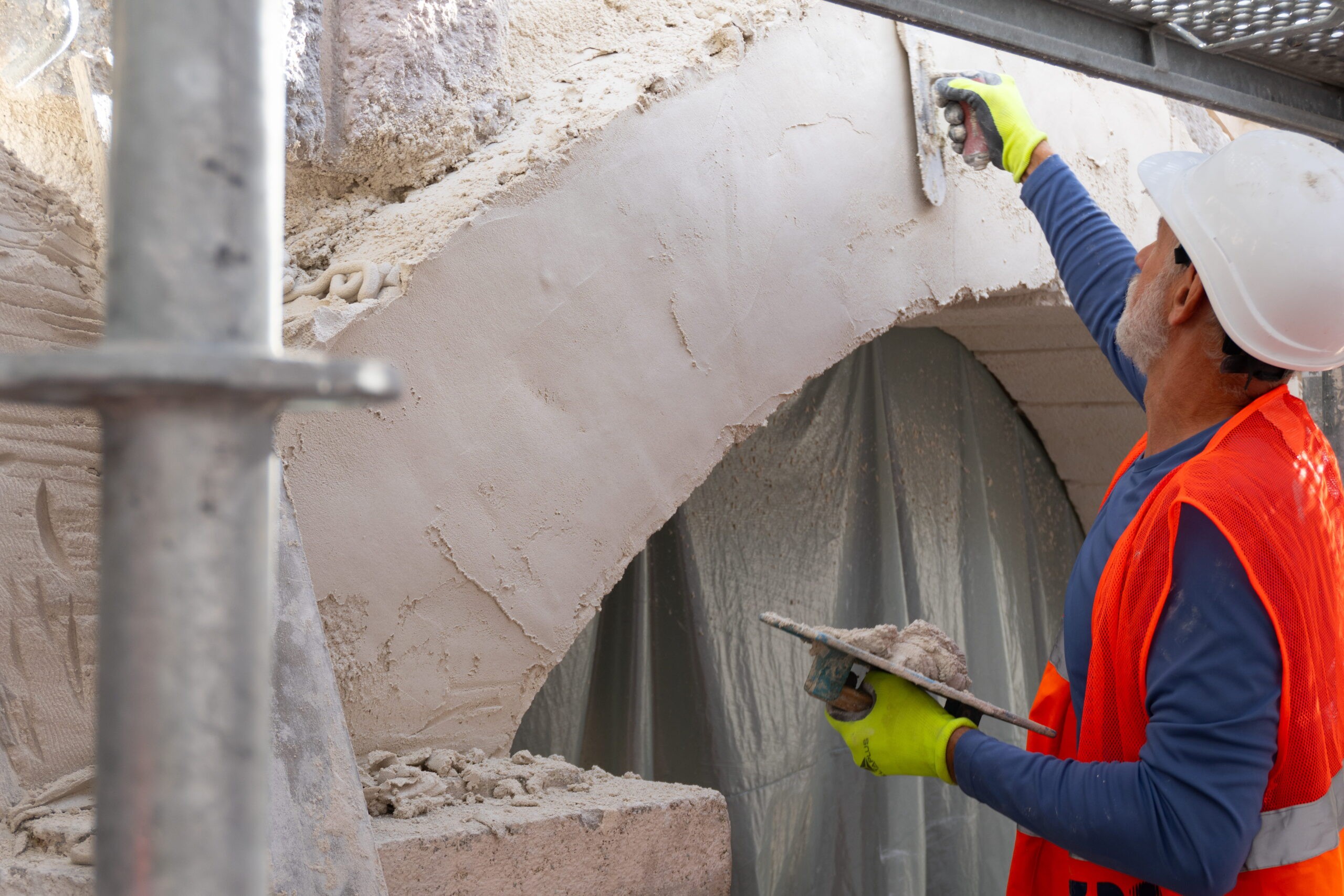 A worker restores the stone finish on a bridge arch