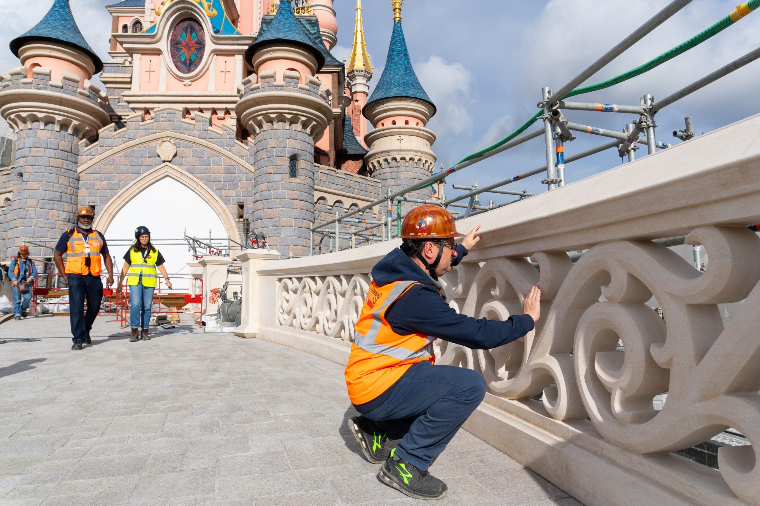 A worker inspects the restored white stone balustrade on the Sleeping Beauty Castle bridge at Disneyland Paris