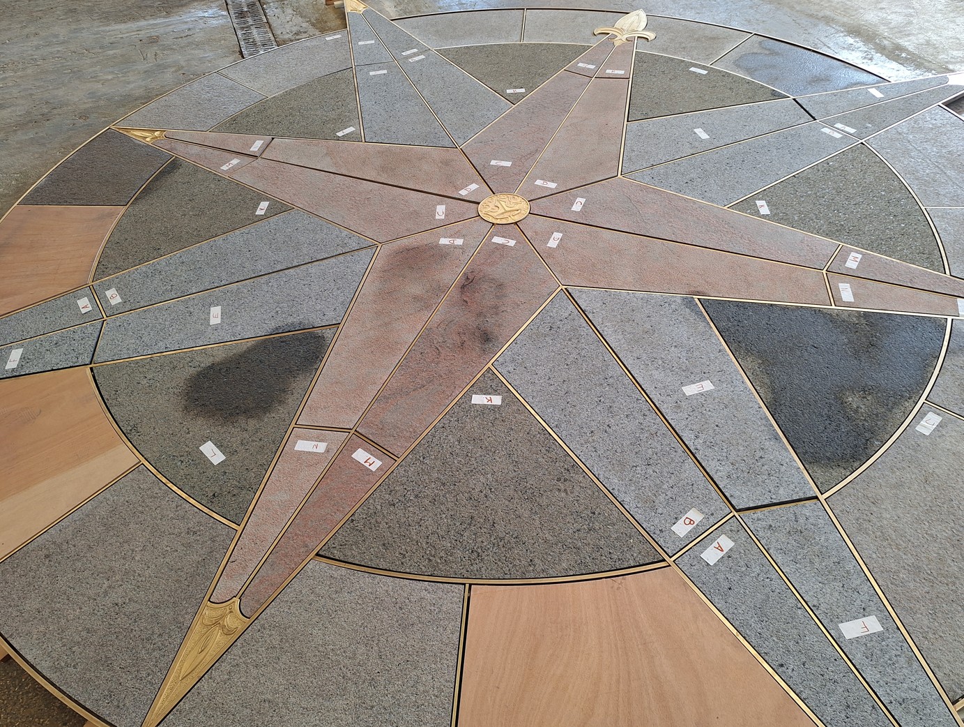 The new granite and brass compass rose laid out in a workshop