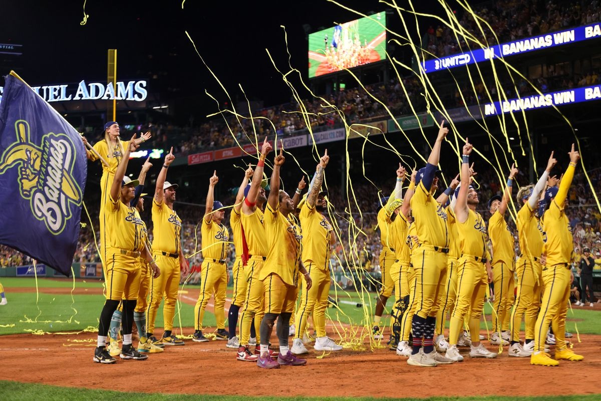 The Savannah Bananas celebrate on a baseball field beneath yellow streamers