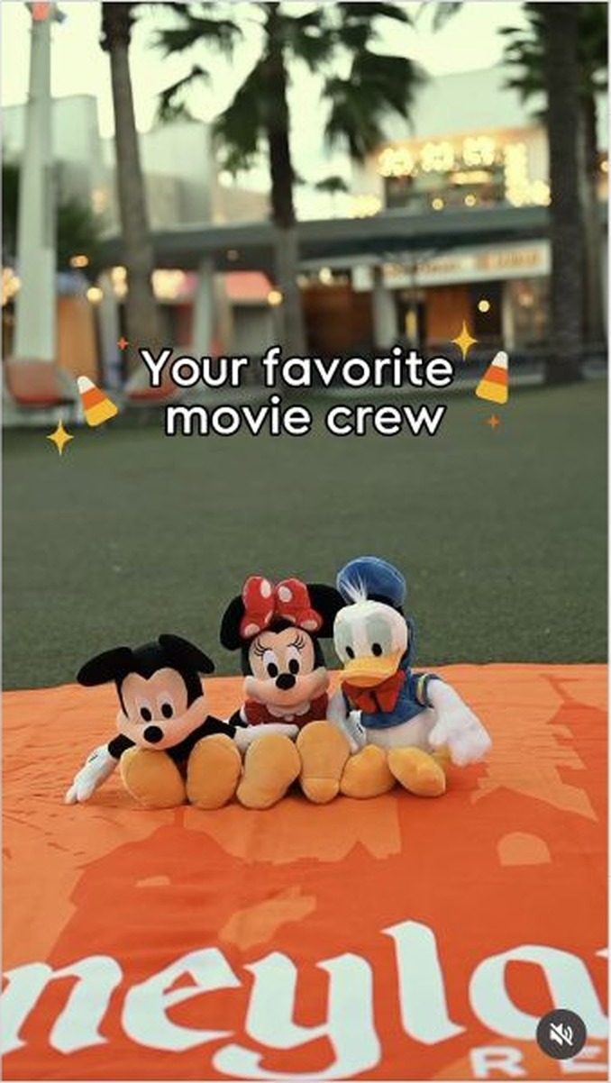 Mickey Mouse, Minnie Mouse and Donald Duck plush sit on an orange Disneyland Resort blanket at Downtown Disney