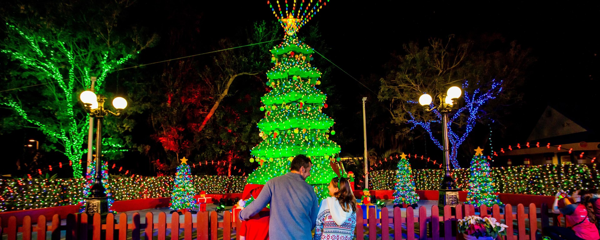 Families look toward a brightly lit LEGO Christmas tree at LEGOLAND Florida