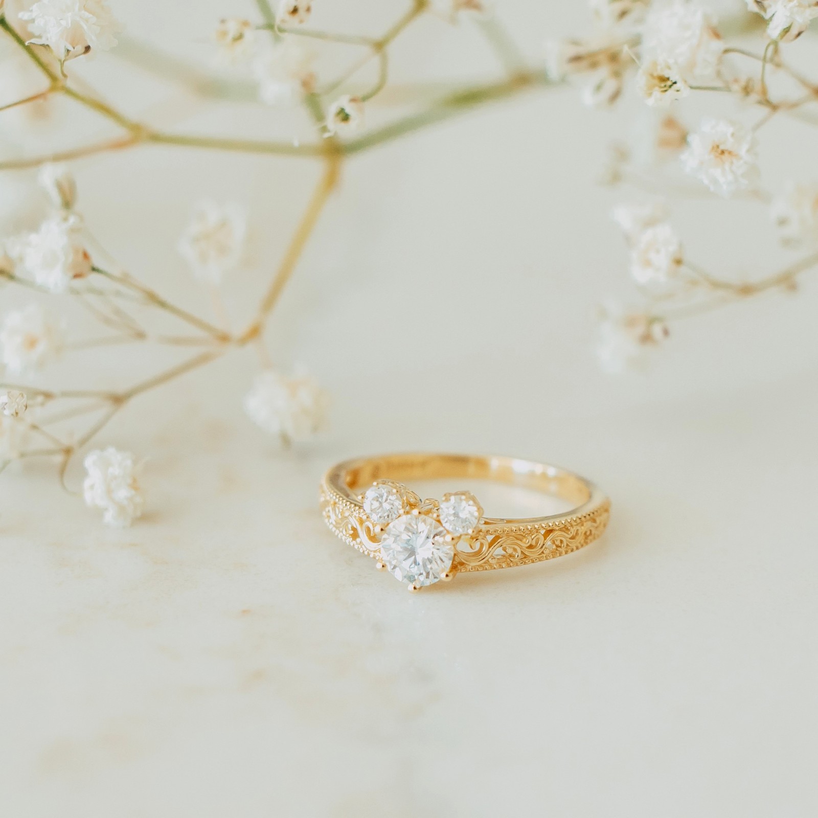 Rebecca Hook Mickey Mouse yellow-gold diamond filigree ring displayed with flowers