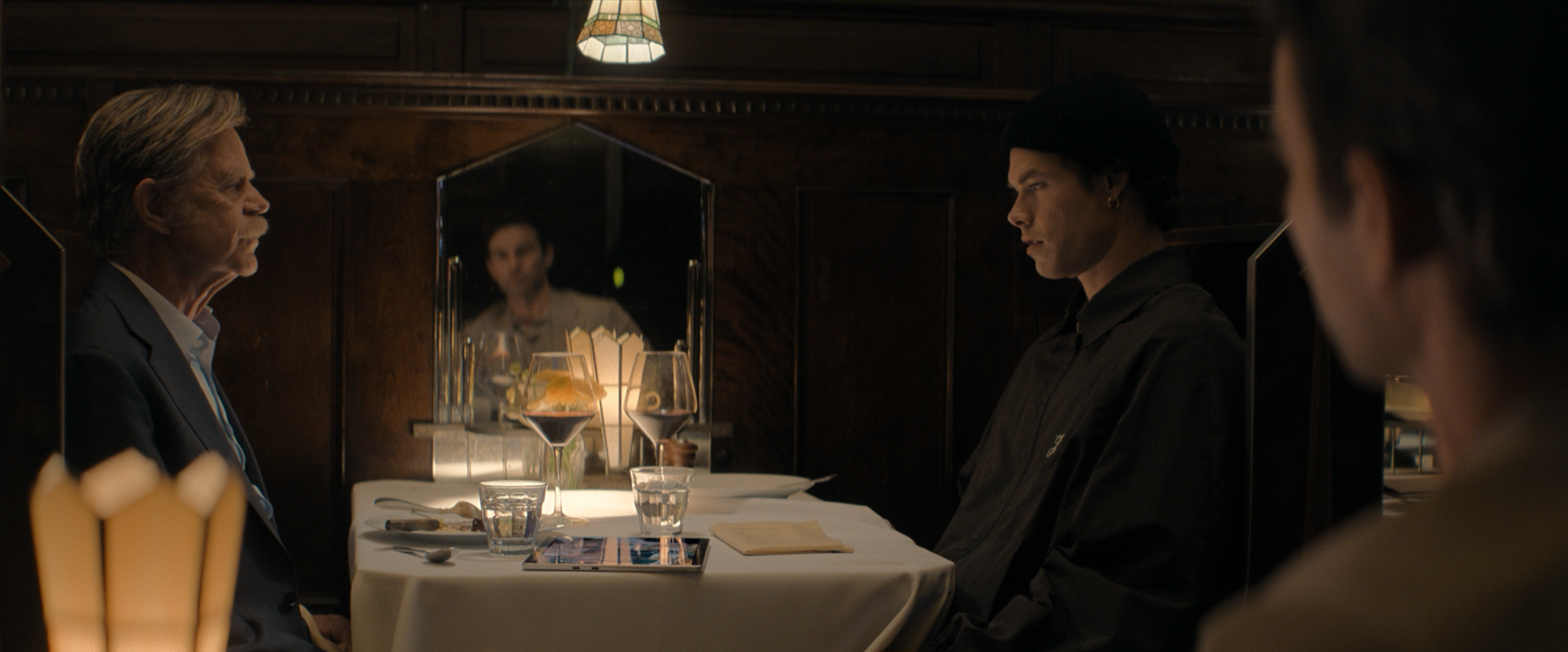A father and son sit across from each other at a restaurant table in The Land