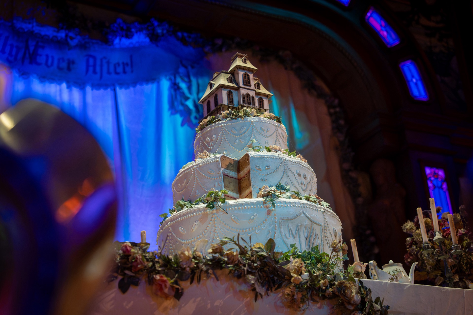 A worn wedding cake topped by a miniature haunted house inside The Unlucky Nugget Saloon